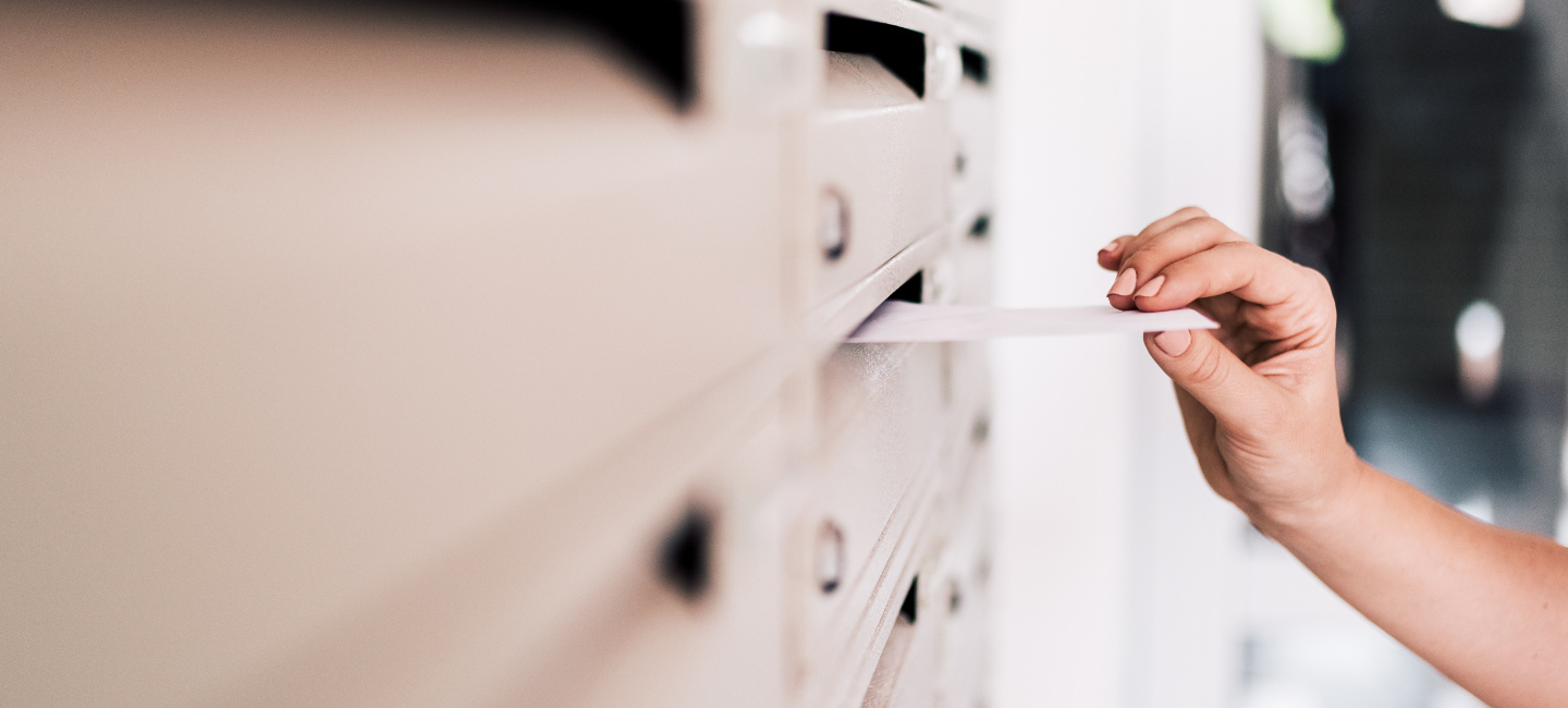 Pessoa a colocar publicidade numa caixa de correio.