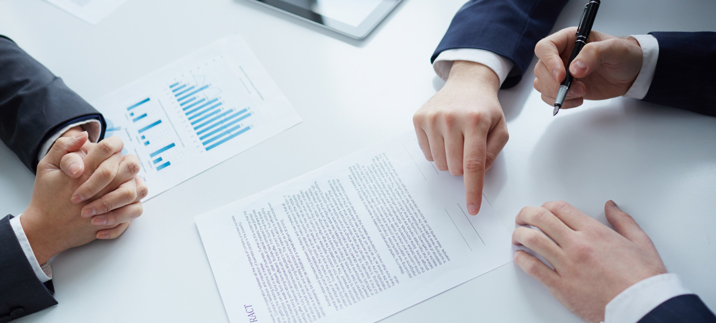 Pessoas com um documento em cima da mesa.