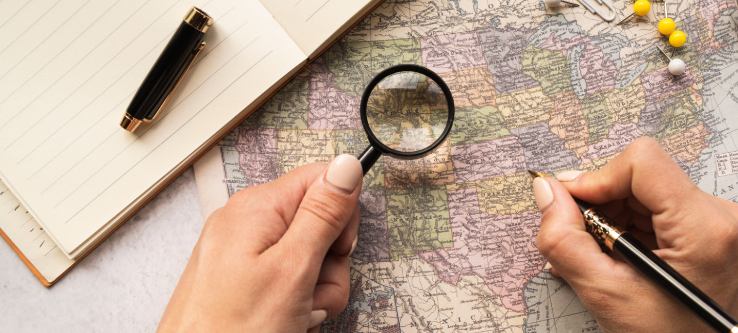 Pessoa a observar mapa mundo com uma lupa