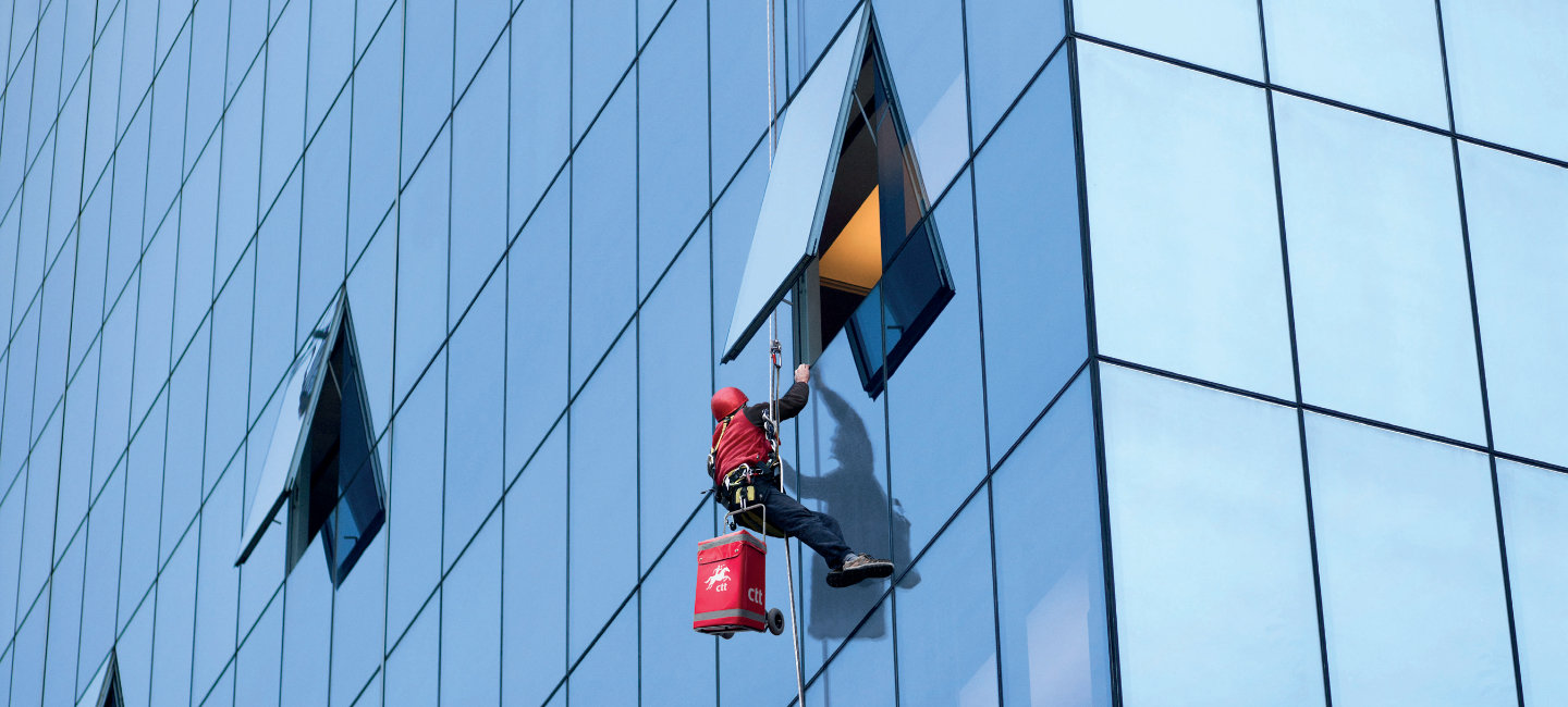 Senhor entrega encomendas a partir de uma janela alta de um escritório.