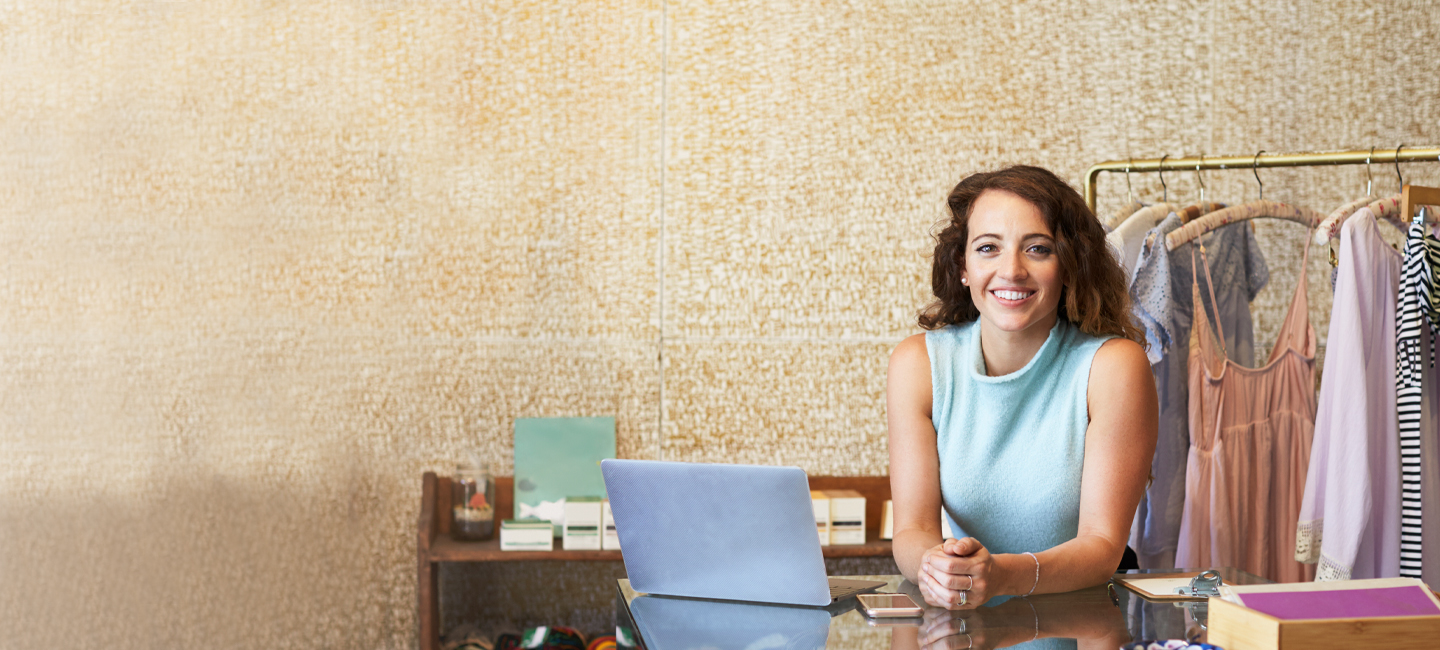 Funcionária de uma loja de roupa, a sorrir.