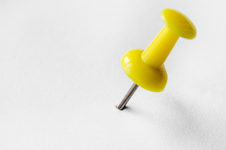 alfinete para quadros, espetado numa folha de papel branca.