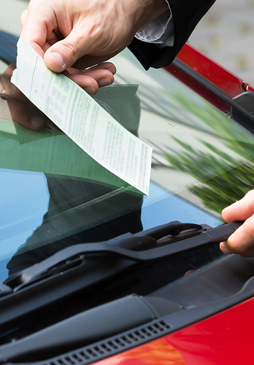 Senhor a retirar o papel da multa que lhe deixaram no limpa vidro do seu carro.