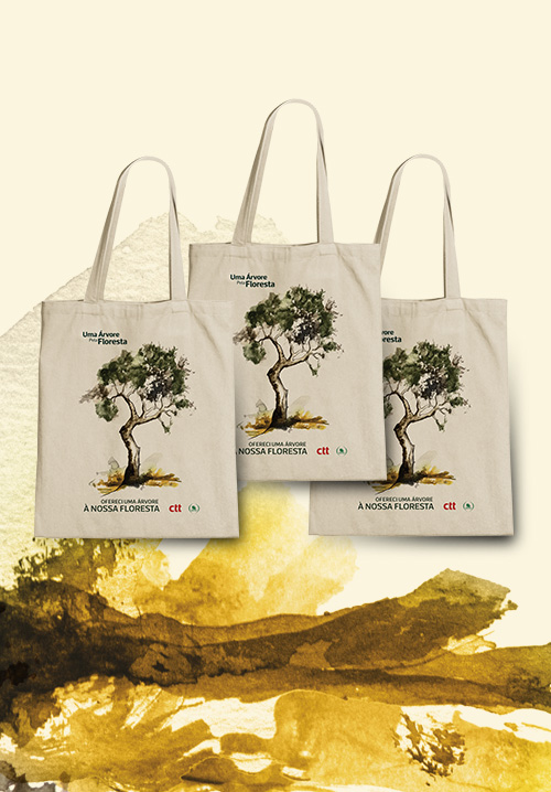 Três sacos de tecido bege (tote bags), todas com o mesmo design impresso. Ilustração de uma árvore no centro. Em cada saco está escrito  “Ofereci uma árvore à nossa floresta”