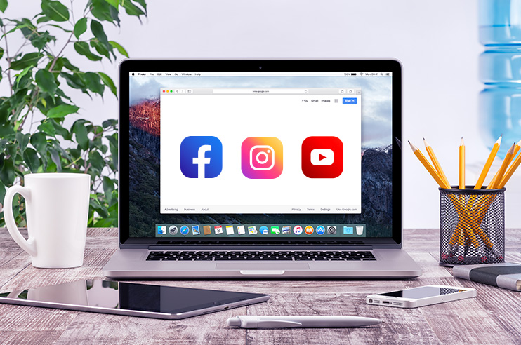 Computador aberto com ícone do facebook, youtube e instagram.