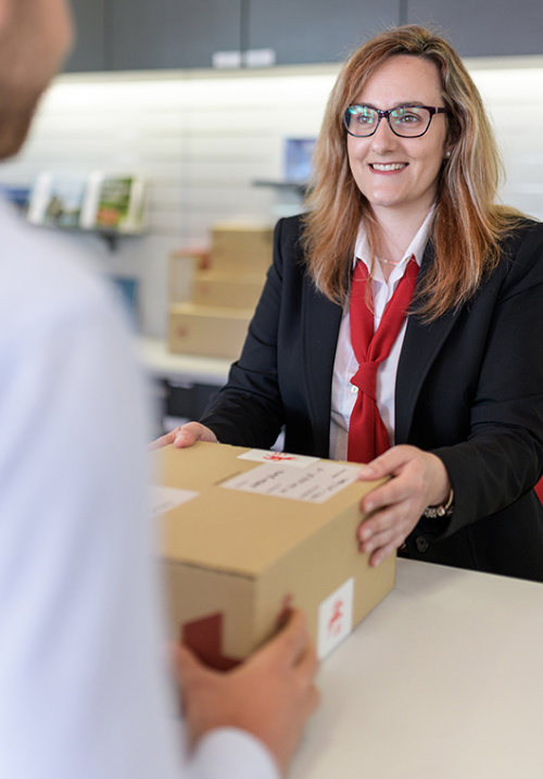 Trabalhadora de uma loja CTT a entregar encomenda a um senhor.